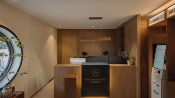 A reception desk with a wooden finish, a digital display, and a potted plant.