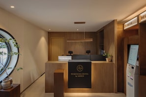 A reception desk with a wooden finish, a digital display, and a potted plant. - Woryeong Hotel By NewCZ (Andong)
