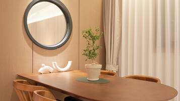 A wooden dining table with chairs, a potted plant, a mirror, and a curtain.
