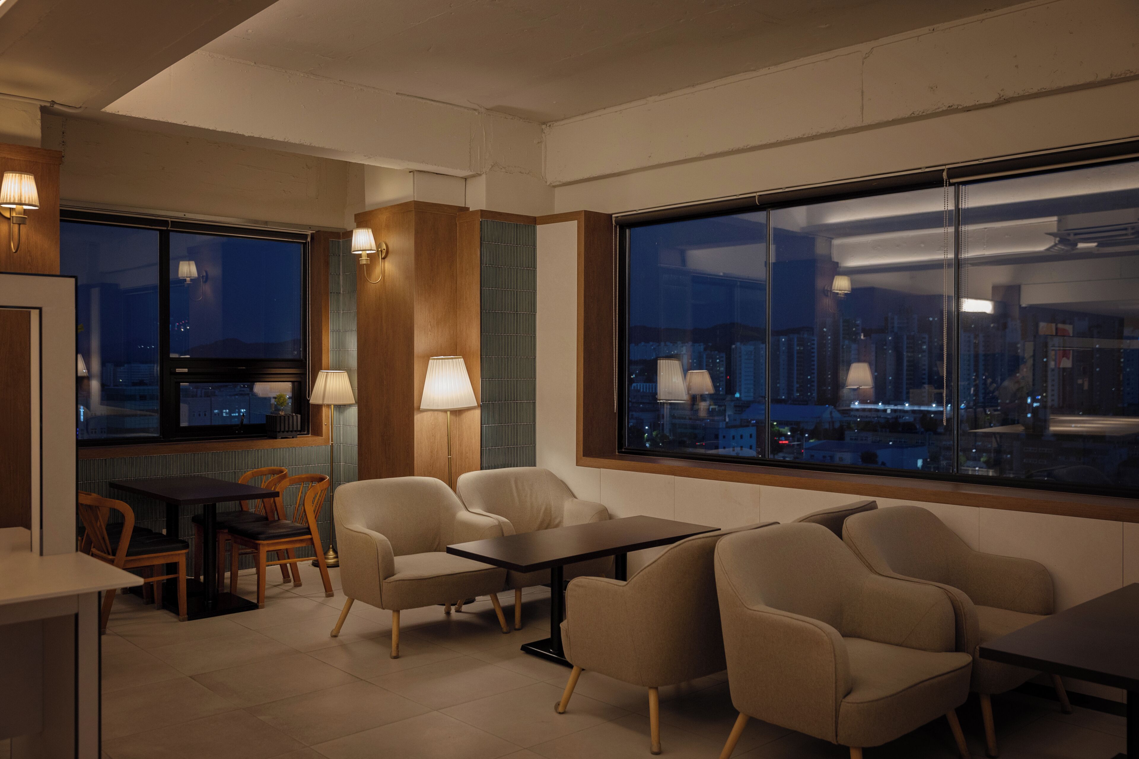 Un interior moderno con una zona de estar, una mesa de comedor y grandes ventanales con vistas a la ciudad.