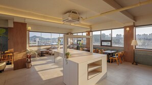A spacious, modern interior with a central island, multiple seating areas, and large windows offering city views. - Woryeong Hotel By NewCZ (Andong)