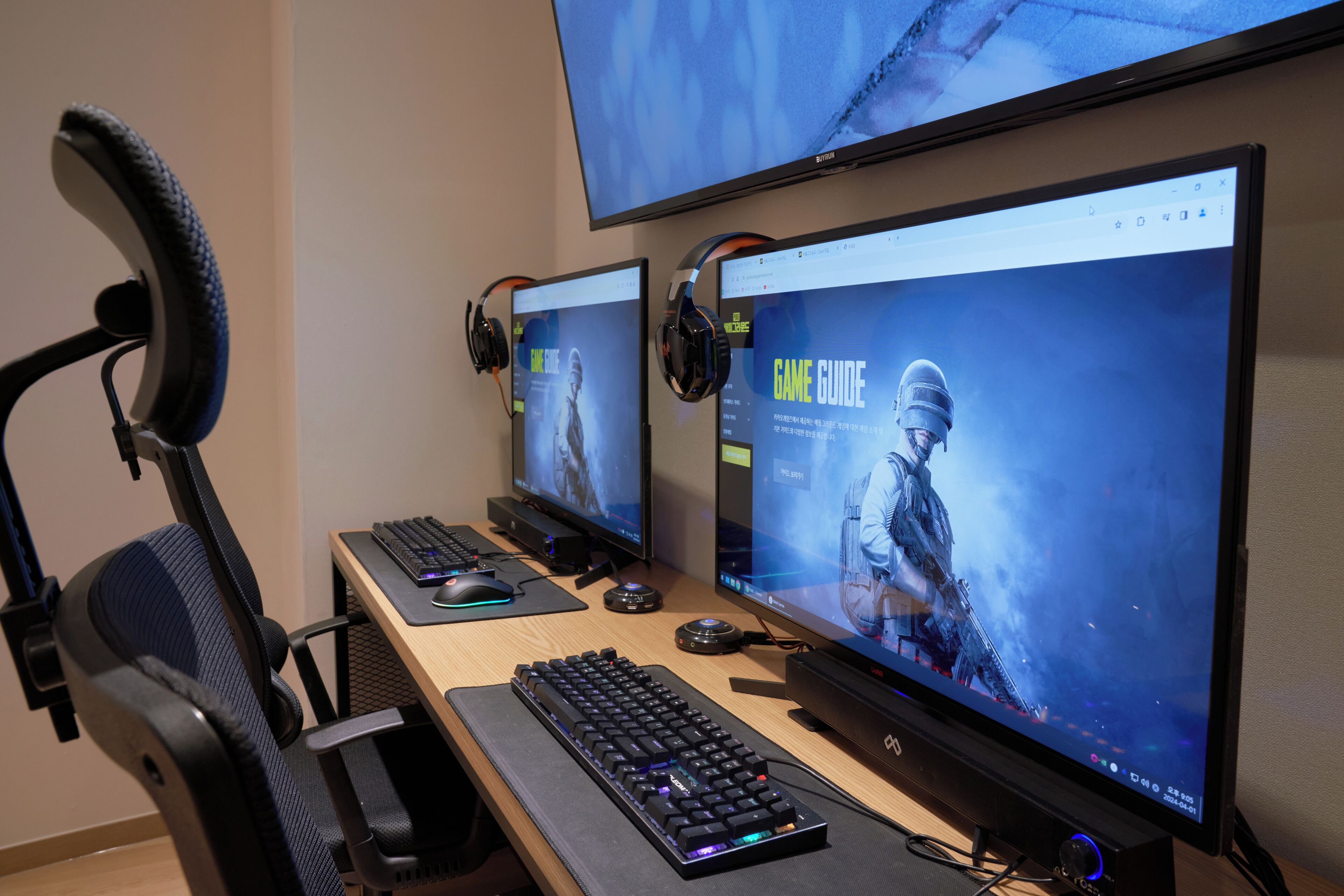 Um espaço gamer com dois monitores, teclado, mouse e fones de ouvido.