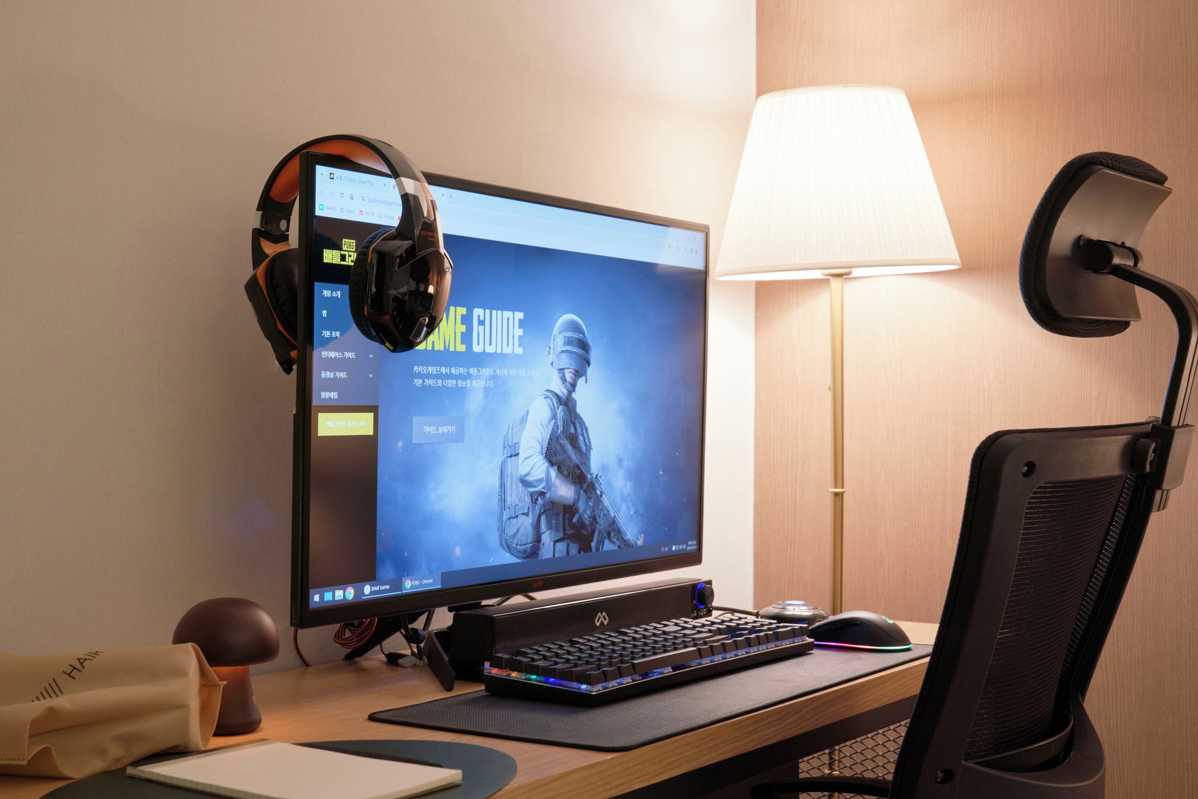 Ein Computerarbeitsplatz mit Monitor, Tastatur, Kopfhörern und einer Schreibtischlampe.
