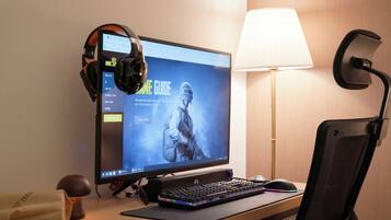 Un ordinateur comprenant un écran, un clavier, un casque et une lampe de bureau.