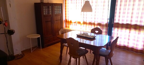 A dining area with a wooden table, four chairs, a cabinet, and a radiator.
