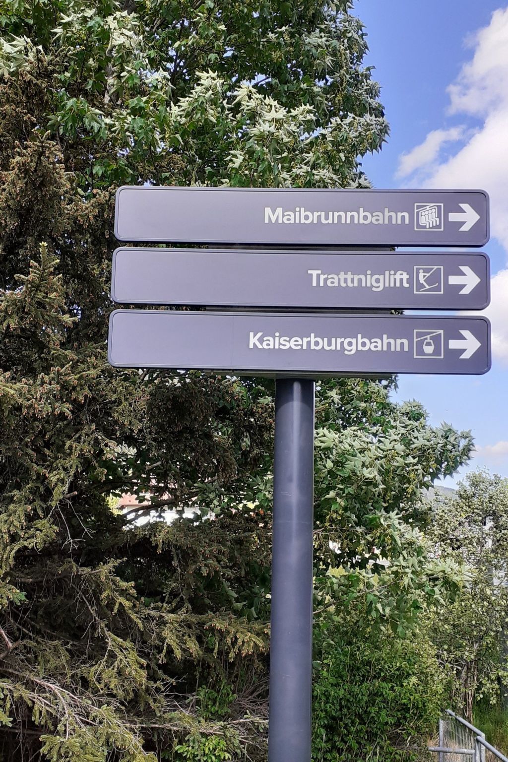 Señal direccional con flechas que indican Maibrunnbahn, Trattniglift y Kaiserburgbahn.