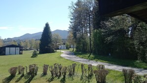 A view of a grassy area with a path leading to a building with a thatched roof. - House Crocus, room no. 12 (Siegsdorf)