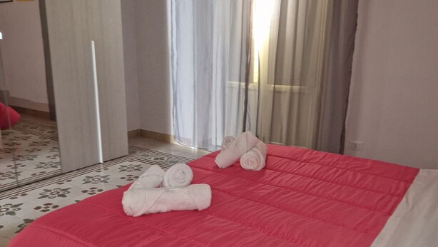 Ein Hotelzimmer mit Bett, Spiegel, Tür und einem fensterbepflanzten Fenster.