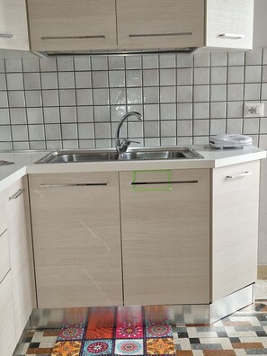 Eine Küche mit Spüle, Schränken und einer gefliesten Spritzschutzwand.