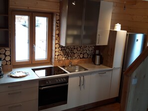 Eine Küche mit Holzschränken, einem Edelstahlkühlschrank, einer Spüle und einem Herd.