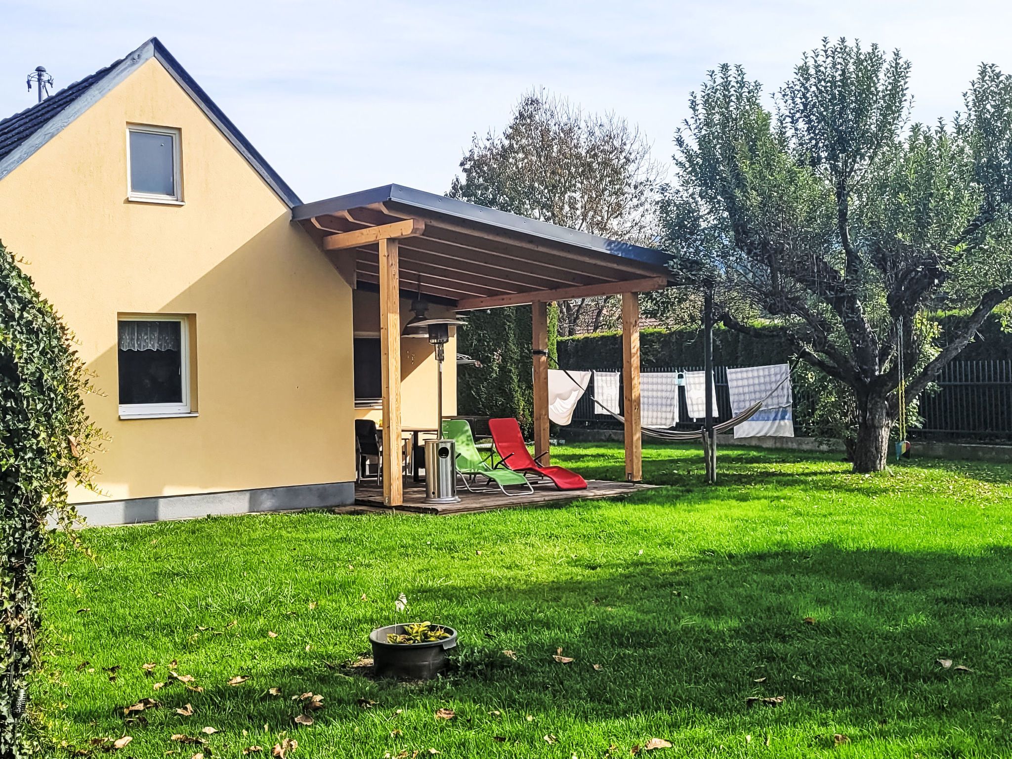 Une maison avec un patio couvert, une pelouse et un arbre.