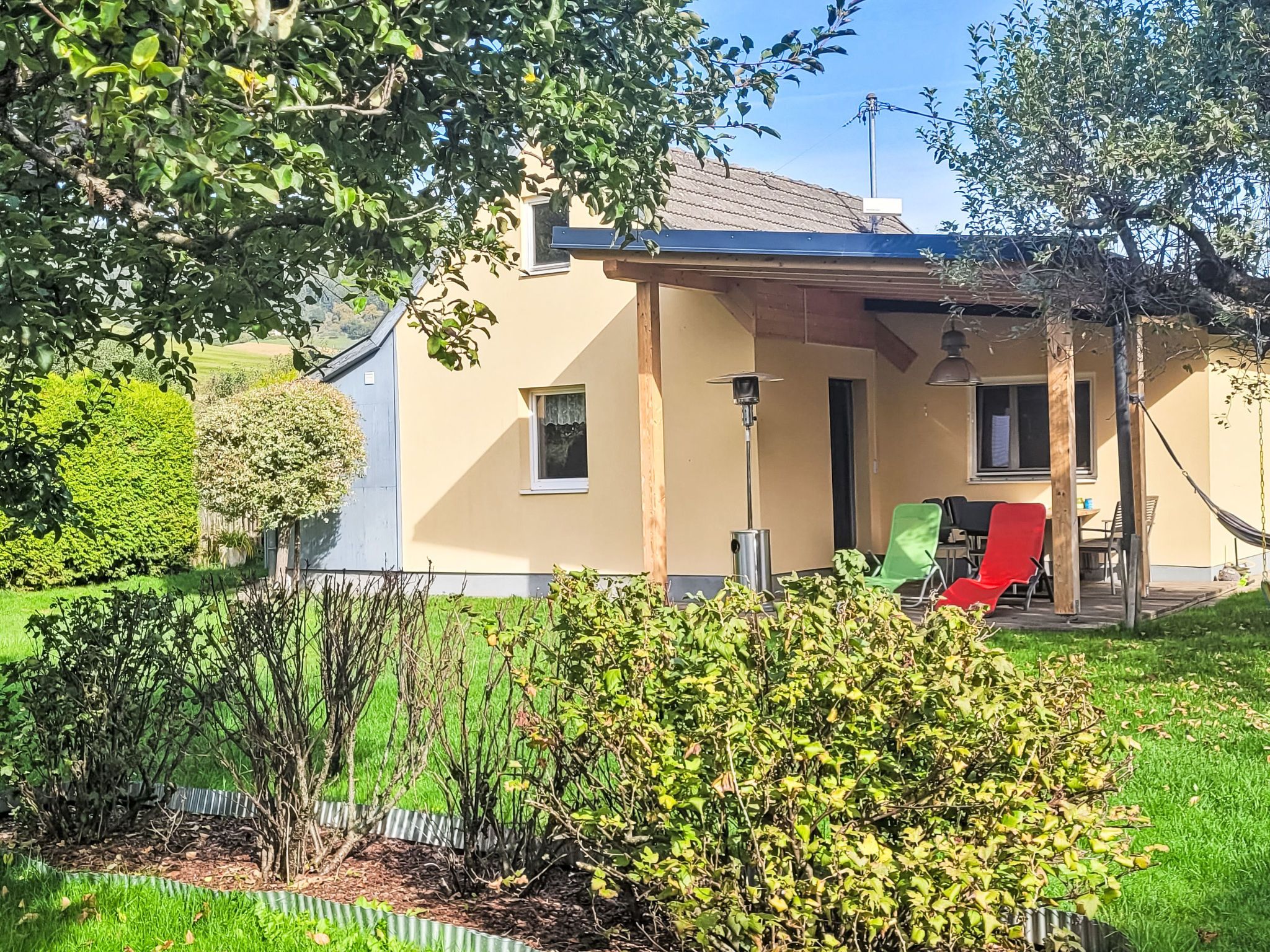 Un edificio residenziale con un portico coperto, un piccolo giardino e un'amaca.