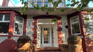 Une maison avec une porte d’entrée, des marches menant à cette porte et une cheminée.