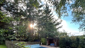 Un jardin avec une piscine, une clôture en bois et une petite construction en bois.