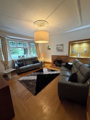 En stue med pejs, to sofaer, et tæppe og en loftlampe.