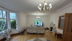 Un salon spacieux agrémenté d’un grand lustre, d’un canapé blanc et d’un tapis à motifs.