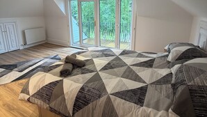 Une chambre avec un grand lit, une vue par la fenêtre et un plafond doté d’un éclairage encastré.