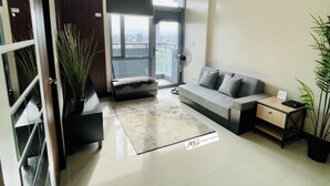 Uma sala de estar moderna com um sofá, uma mesa de centro, uma mesinha lateral, uma planta em vaso e uma janela grande com vista.