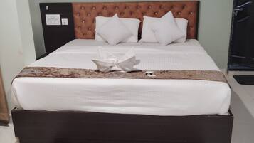 Una cama bien hecha con una colcha estampada, un arreglo decorativo de almohadas y una alfombra estampada en rojo y blanco en el suelo.