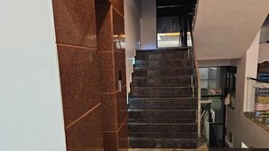 A modern interior with a marble floor, a staircase, and a reception desk. - Hotel Gokarna Palace (Ankola)
