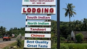 A signboard for a restaurant and lodging with multiple language options and vegetarian options. - Hotel Gokarna Palace (Ankola)