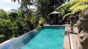 A clear pool with a stone edge, surrounded by lush greenery and a stone statue. - Room-private Villa Room With Nature View (Ubud)