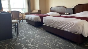 Ein Hotelzimmer mit zwei Betten, einem Schreibtisch, einem Stuhl und einem Vorhangfenster.