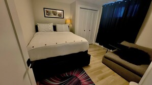Una camera d'albergo con un letto, un divano, una TV, una lampada, una porta e un tappeto decorato.