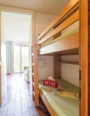 Ein Schlafraum mit Etagenbetten und einer Schiebetür, die auf einen Balkon führt.