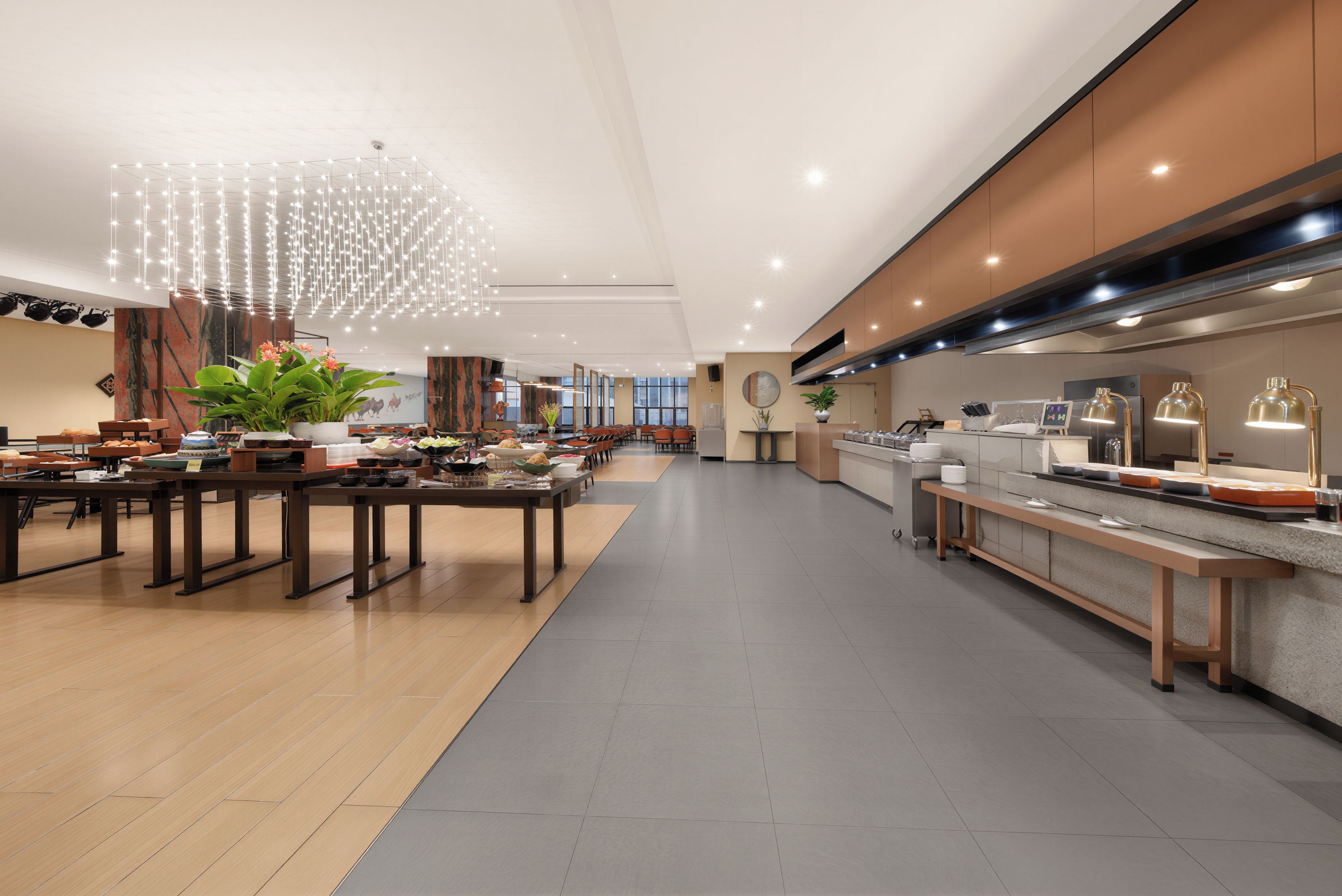 A spacious hotel lobby with a long reception desk, multiple seating areas, and a modern chandelier.