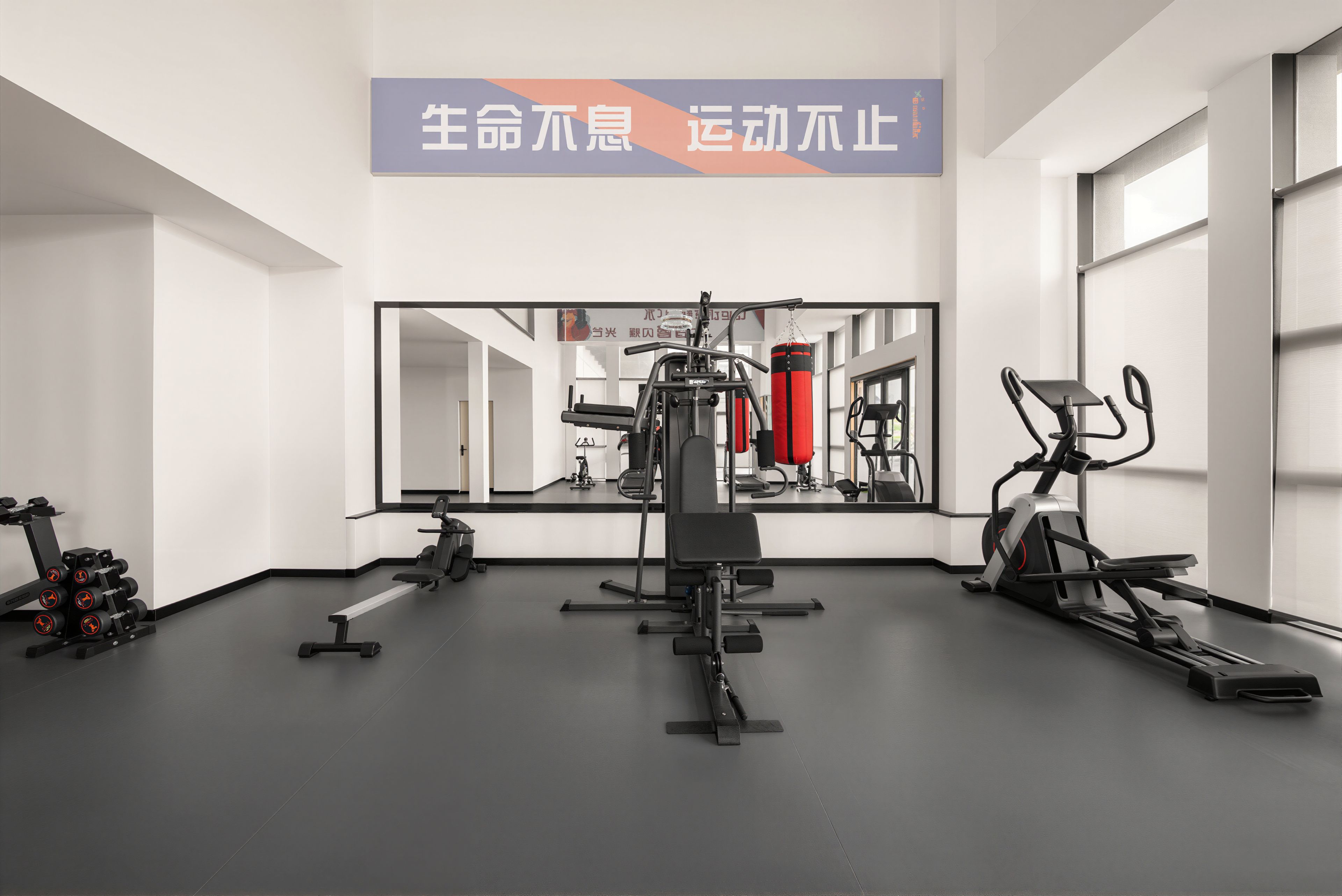 Un gimnasio con equipo de ejercicio, una banca y un espejo grande.