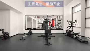 Un gimnasio con equipo de ejercicio, una banca y un espejo grande.
