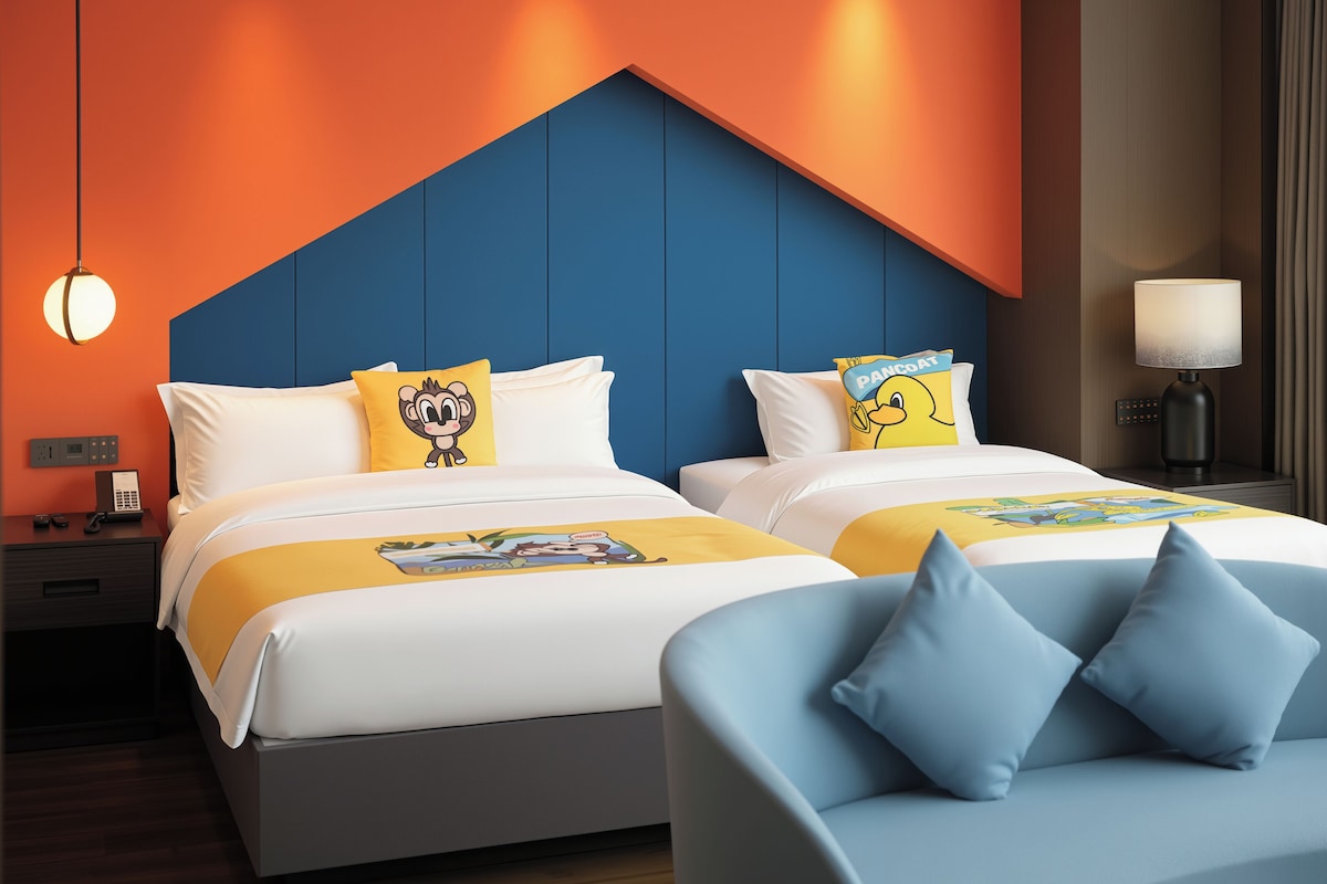 A hotel room with two beds, a blue accent wall, and a nightstand with a lamp.
