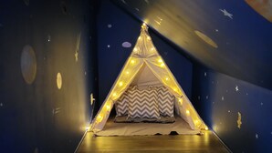 A tent-like bed with star decorations and string lights, set against a dark blue wall with celestial patterns. - Mountain Jewel - Lake & Mountain View - Romantic Retreat w/ Cozy Space Nook (Sevierville)