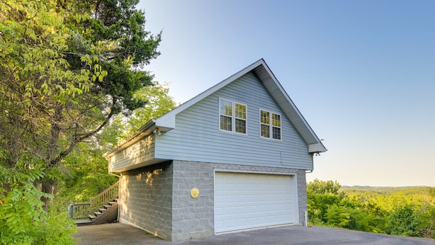 A two-story house with a garage, surrounded by trees. - Mountain Jewel - Lake & Mountain View - Romantic Retreat w/ Cozy Space Nook (Sevierville)