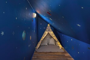 Una habitación con techo estrellado, una cama tipo tienda y suelo de madera.