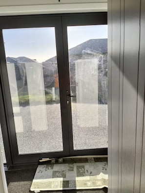 Une pièce dotée d’une porte-fenêtre coulissante donnant sur un espace recouvert de gravier, avec vue sur la montagne.