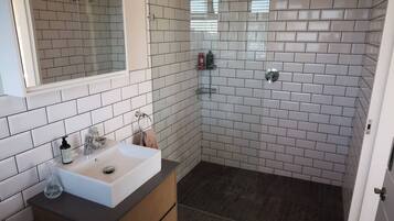 Une salle de bain avec un lavabo blanc, un miroir et des murs carrelés.
