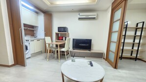 A compact living space with a dining table, a TV, a microwave, and a washing machine. - Yeoksam Gangnam 5min Cozy Urban Signature Stay (Seoul)