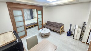A compact hotel room with a bed, sofa, table, and a small kitchenette area. - Yeoksam Gangnam 5min Cozy Urban Signature Stay (Seoul)