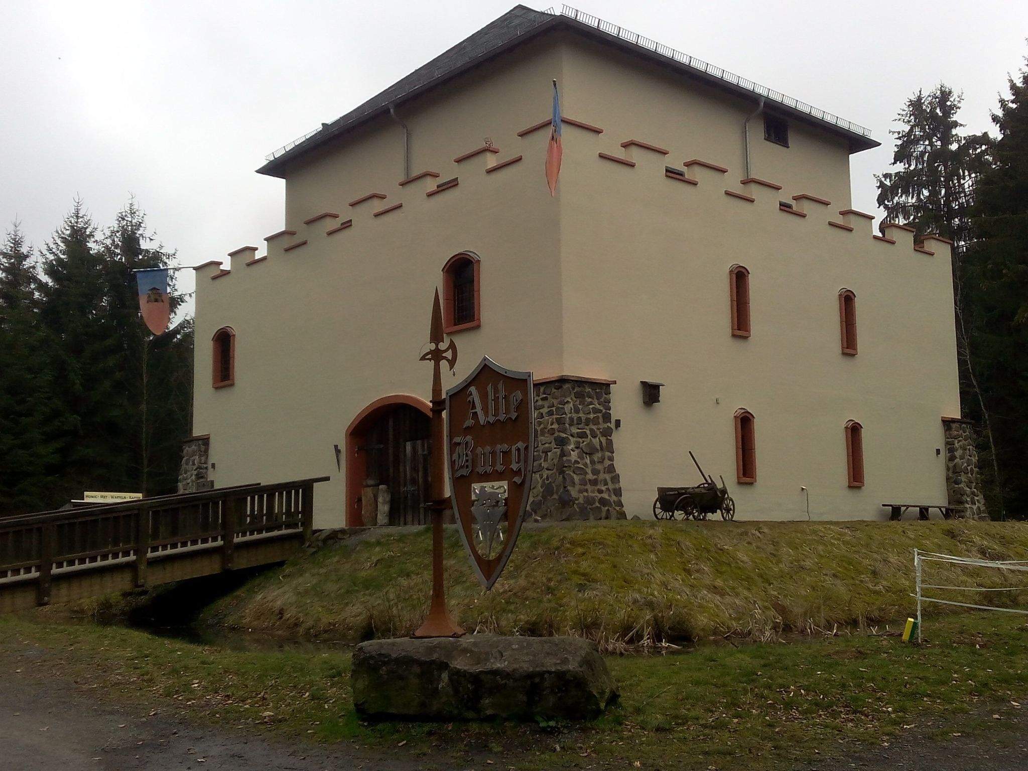 Ein Gebäude mit rustikalem Steingrund und einem hellbeigen Obergeschoss, das einen großen Bogenbogen und zahlreiche Fenster aufweist.