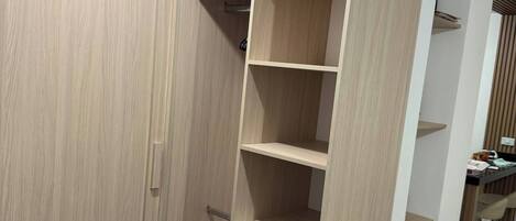 A walk-in closet with multiple shelves and drawers, a hanging rod, and a door with a handle.