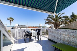 Ein Balkon mit Tisch und Stühlen, einer grünen Bank und einer Wand mit Muster.