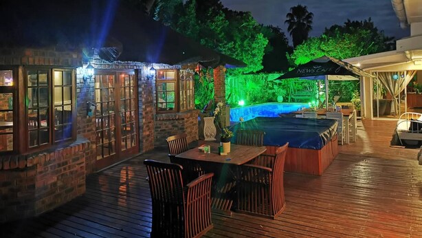 Patio esterno con piscina, terrazza in legno e area bar.
