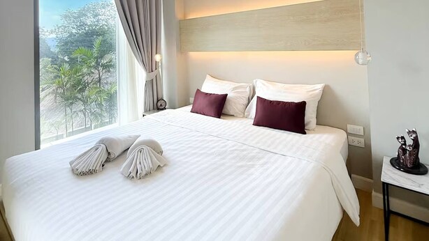 Una habitación de hotel moderna con una cama grande, vistas a zonas verdes y un aplique de techo.