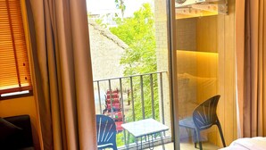 A hotel room with a balcony, a bed with a towel, a table, and chairs.