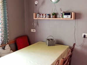 A small room with a table, chairs, a shelf with various items, and a power outlet. - Mayrhansahof in Altenmünster by Interhome (Altenmünster)