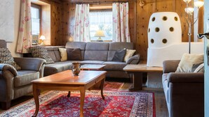 Una habitación acogedora con techo de madera, un conjunto de sofá, una mesa de centro y una alfombra estampada.
