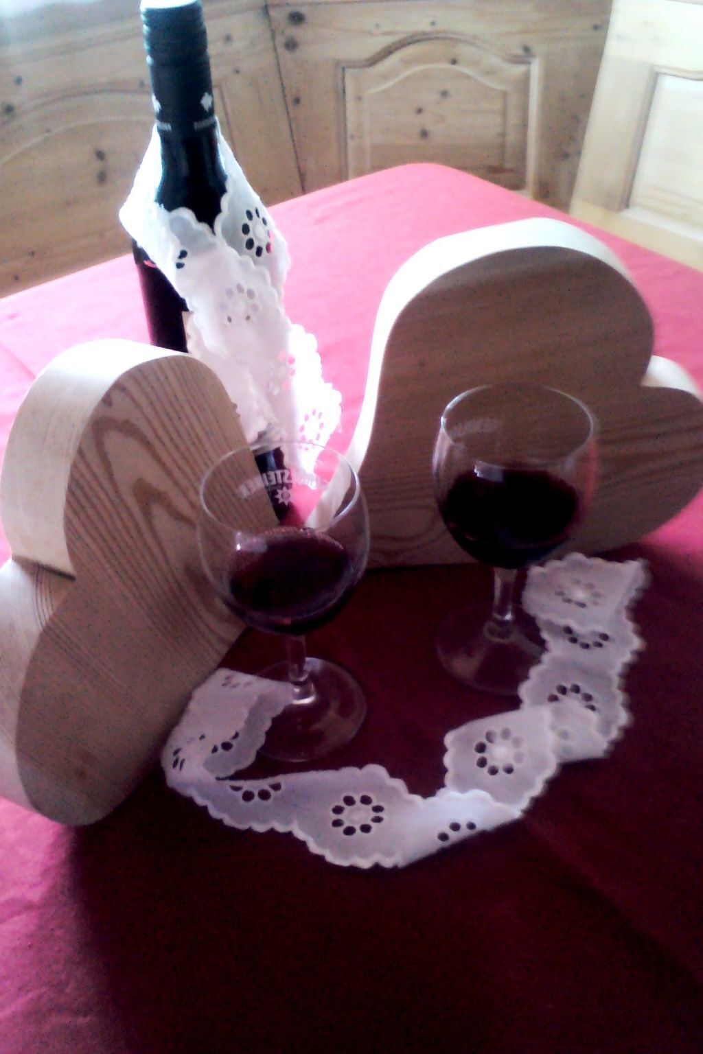 A table with a bottle of wine, two glasses, and a lace doily.