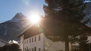 Una carretera cubierta de nieve que lleva a un edificio, con una montaña al fondo.